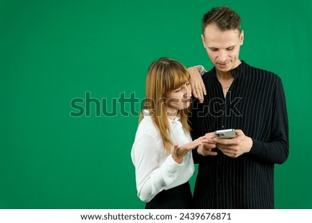 man and woman with gadgets tablet phone in hands on green background talking laugh holding meeting learning to work on Internet flirting relationships flirting couple solving issue positive emotions