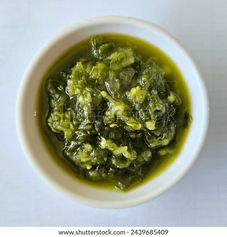 Green chili sauce which is made from large green chilies mixed with other ingredients such as green cayenne peppers, red chilies, garlic and green tomatoes