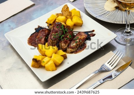 Close up of delicious baked pork with potatoes, served on plate