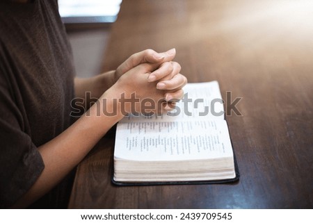 Christian woman's hands resting on a Bible pleading with God.