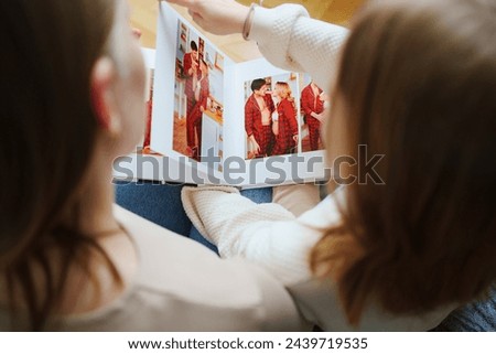 mother and daughter flips through a photo book with photos of dad and pregnant mom. Beautiful memory. Professional photo printing. services of photographer and designer. original gift for the family.