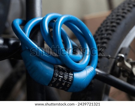 Blue flexible bike lock with code set that hangs on the metal frame of a  bike