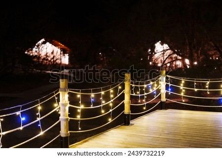 Terrace with light bulbs in glamping. Cabins for recreation in the forest. Night landscape.