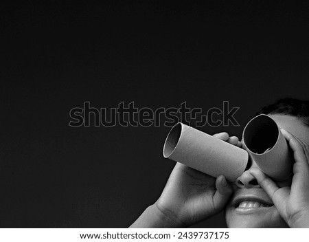 boy looking  through toy binoculars made from toilet paper roll on grey background with people stock image stock photo