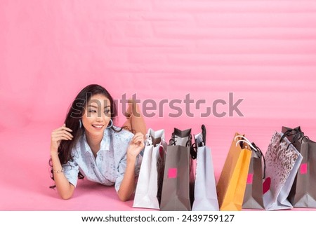 Portrait of an excited beautiful girl holding shopping bags isolated over pink background