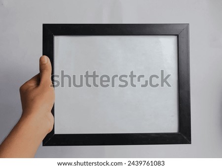a black photo frame held in one hand, and a white background
