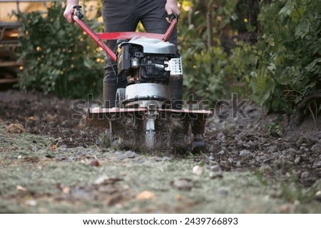 Farmer man plows the land with a cultivator preparing the soil for sowing. Royalty-Free Stock Photo #2439766893