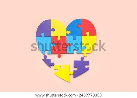 Heart made of color puzzle on beige background. Concept of autistic disorder