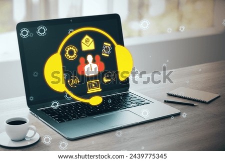 Close up of laptop and coffee cup on office desk with creative customer support icon on blurry background. Hotline concept