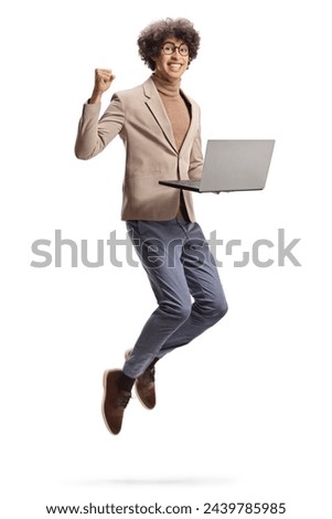 Excited young man jumping with a laptop computer isolated on white background