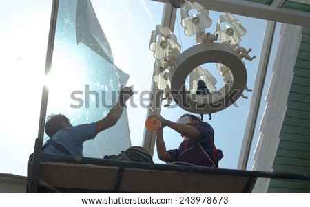 unidentified  people wrappers tinting a glass house window with a tinted foil or film using foggy spray Royalty-Free Stock Photo #243978673