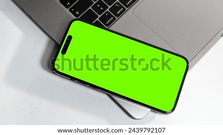 a green screen phone mockup placed on top of a laptop