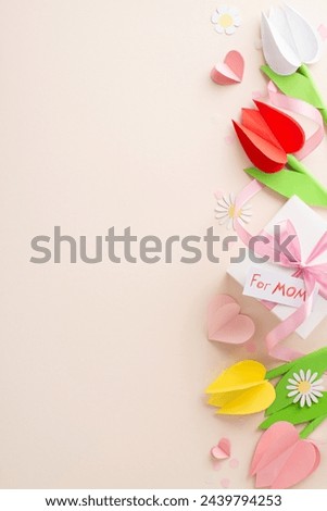 Artful Mother's Day greeting, top view vertical photo of origami tulips, chamomiles, crafted gift box with "for mom" signage, bound with ribbon, paper hearts, subtle confetti on blush beige surface