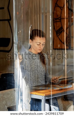 Tarot cards with blue and yellow pictures in the hands of a serious girl in a gray sweater with her hair in a ponytail during the ritua in Granada, Spain 