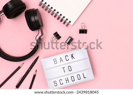 Back to school. Lightbox with letters, headphones and stationery on a pink background. Place for text.