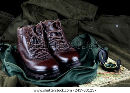 Old hiking boots with old map and compass on a game bag and outdoor field coat