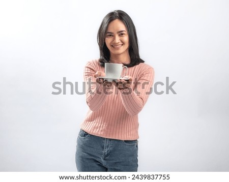 Portrait of an Indonesian Asian woman, wearing a pink sweater, enjoying a drink with a cup, isolated against a white background.