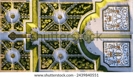 Aerial view of the ornate and symmetrically designed gardens of Hillerød Castle in Denmark, captured in the warm light of the sun, highlighting the intricate patterns and landscaping artistry
