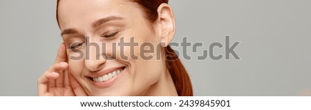 pleased and redhead woman in white tank top with a tender healthy smile on a grey background, banner