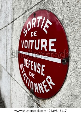 road sign with the French writing SORTIE DE VOITURE, DEFENSE DE STATIONNER which means exit car, no parking