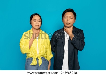 A millennial japanese woman and a man in vibrant attire appear distressed, with the woman clutching her throat and the man holding his neck, both displaying signs of choking or discomfort