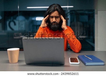 Anxious male experiencing stress while working on laptop, displaying hands on head Royalty-Free Stock Photo #2439852611
