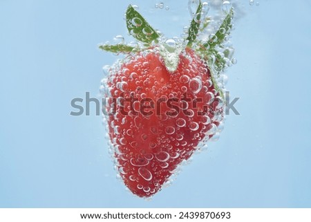 Macro shot of a strawberry in sparkling mineral water. Close up on details of a berry and water bubbles.  Royalty-Free Stock Photo #2439870693
