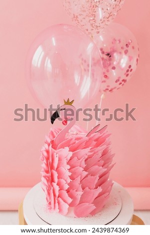 Cute pink cake with flamingo on paper pink and balloons background in studio