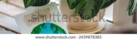 Children's craft for the Earth Day celebration. Little boy holding handmade simple postcard with picture of Planet made of plasticine. Concept of environment education for kids in kindergarten. Banner