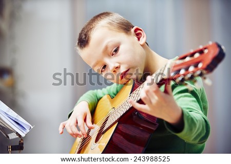 Little boy is playing the guitar at home Royalty-Free Stock Photo #243988525