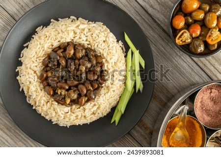 Black soybeans cooked in spices served with brown basmati rice and celery stalks. Bhat ki Chudkani - a traditional dish of the Kumaon region. Pickled chilies and a box with spices on the side. Royalty-Free Stock Photo #2439893081