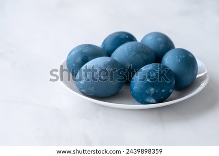 Blue colored Easter eggs on white table on neutral marble table background, traditional Easter holiday homemade decorated food, soft selective focus.
