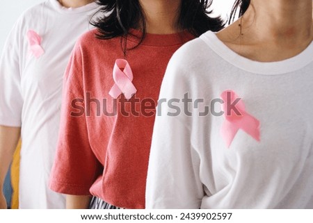 Unrecognize women standing in a row with pink ribbon on their chest. October breast cancer awareness month and World Cancer Day concept