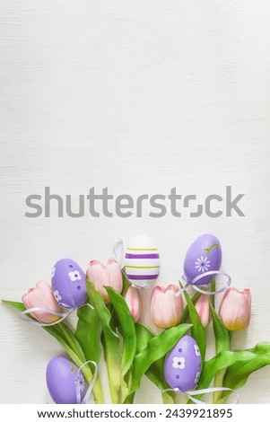 Happy Easter holidays greeting card concept: Bouquet of pink tulips and easter eggs on a white background; copy space, vertical picture