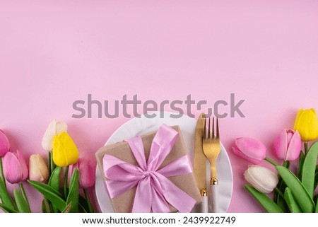 Mother day table setting background. Pink Mother's day border flat lay for brunch, lunch, dinner menu, invitation mockup. Beautiful table setting with golden cutlery, plate, tulip flowers and gift box Royalty-Free Stock Photo #2439922749