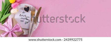 Mother day table setting background. Pink Mother's day border flat lay for brunch, lunch, dinner menu, invitation mockup. Beautiful table setting with golden cutlery, plate, tulip flowers and gift box Royalty-Free Stock Photo #2439922775
