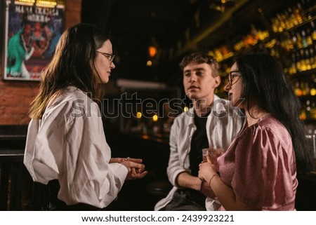 Guy attracted by pretty lady in pub. Happy people have fun before weekend in chic restaurant with trendy picture in background