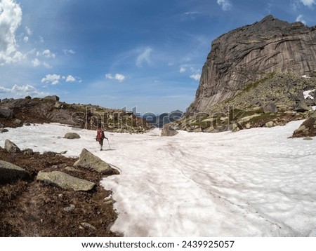 Tourist in walks on snow mountain near abyss edge on high altitude under blue sky in sunny day. Difficult climb to the top of the mountain. Travel lifestyle, solo hiking hard track, adventure concept