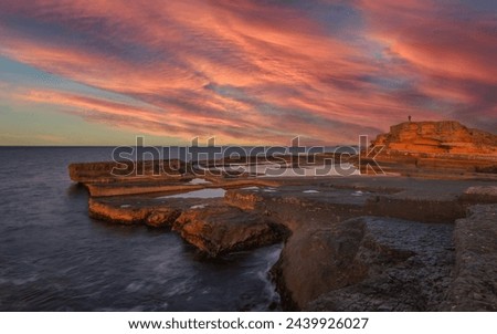 sunset light and unique shaped cliffs by the sea colorful clouds in the sky