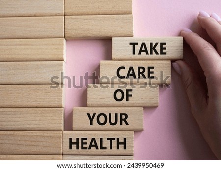 Health symbol. Wooden blocks with words Take Care of your Health. Doctor hand. Beautiful pink background. Health concept. Copy space.