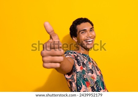 Photo of excited funky man wear print t-shirt showing you thumb up isolated yellow color background
