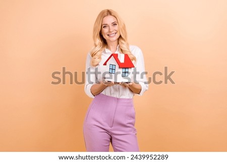 Photo of good mood cheerful lady dressed white shirt holding arms hands small house isolated beige color background