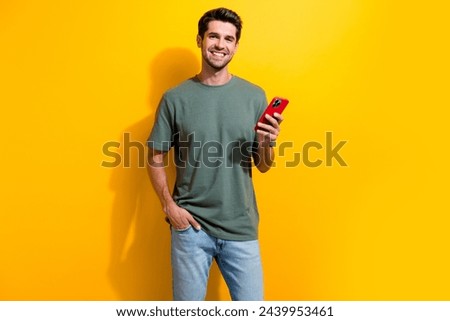 Photo of clever smart man with bristle dressed khaki t-shirt hold smartphone keep hand in pocket isolated on yellow color background
