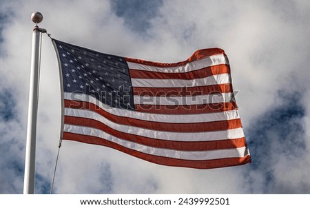 An American flag blowing in the wind on a windy and cloudy day 
