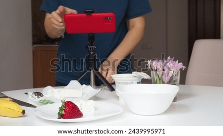 girl blogger films breakfast for video blog, content for social networks, stories. Hands with the phone close-up pictures of food. Breakfast for two : yogurt, coffee, fruit ,  strawberry, banana