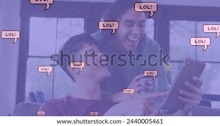 Image of lol text in speech bubbles over diverse male couple using tablet. Global social media, technology and digital interface concept digitally generated image. Royalty-Free Stock Photo #2440005461