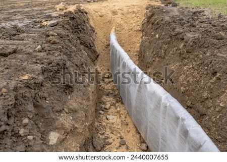 Construction photo of natural turf athletic field vertical edge drain profile, drainage panel between baseball - softball infield clay and natural grass field.