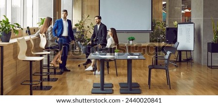 Team of smart business people communicates and discusses work issues in office of business center. Male and female colleagues talking after business meeting. Business concept. Banner image.