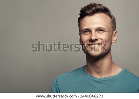 Male beauty concept. Portrait of smiling 30-year-old man standing in blue t-shirt over gray background . Close up. Classic style. Wavy glossy blond hair. Studio shot Royalty-Free Stock Photo #2440046293