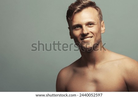 Male beauty concept. Portrait of smiling 30-year-old sportsman posing over light gray background. Close up. Copy-space. Athlete style. Wavy glossy blond hair. Studio shot Royalty-Free Stock Photo #2440052597